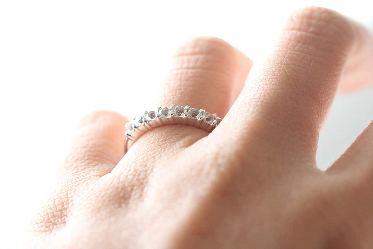 close up image of a woman’s hand with a diamond eternity ring on the left ring finger