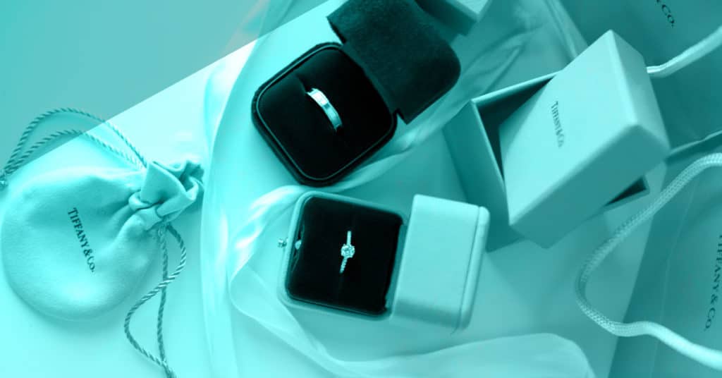 men’s and women’s engagement rings in blue Tiffany boxes with Tiffany bags on white background