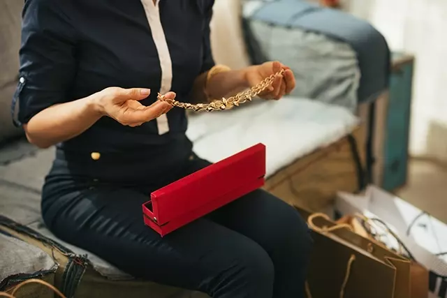 Woman unpacking gold necklace from box