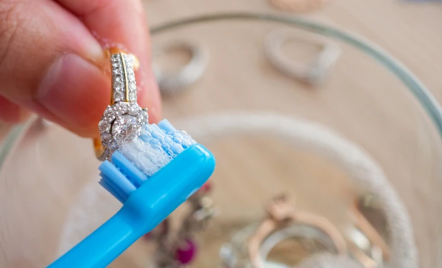 Close up of a hand cleaning a ring using a toothbrush