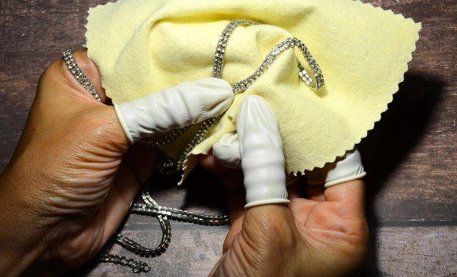 Close up of hands using a polishing cloth to clean a silver necklace