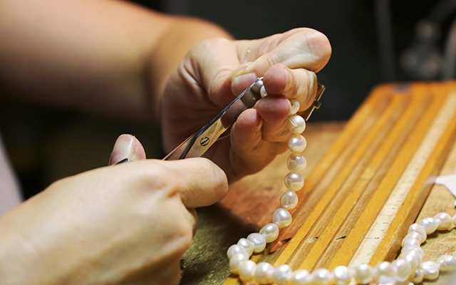 A person repairing a pearl necklace