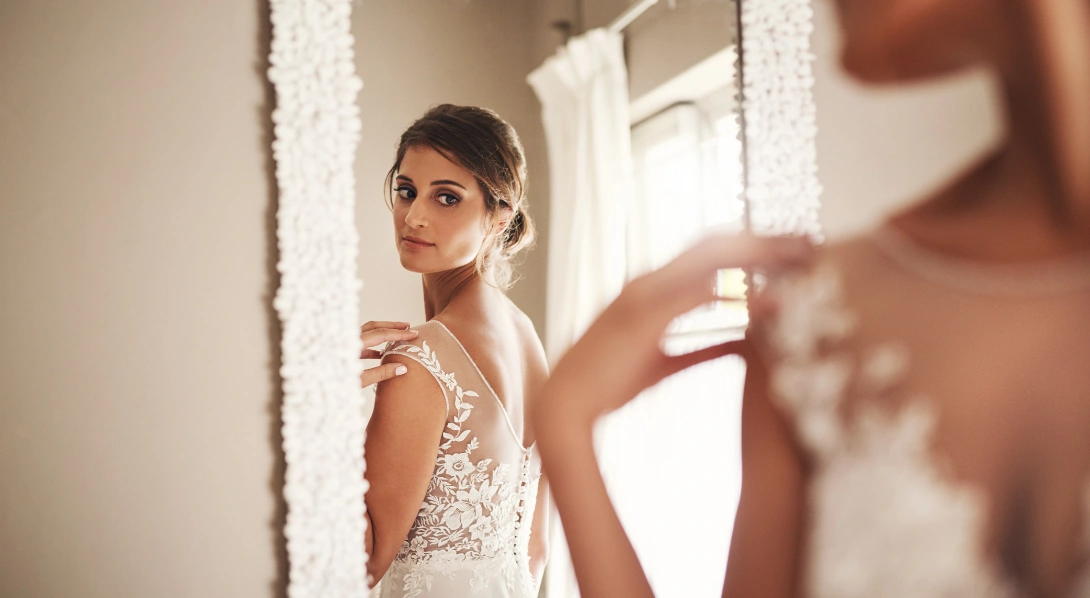 Frustrated bride looking at phone in mirror