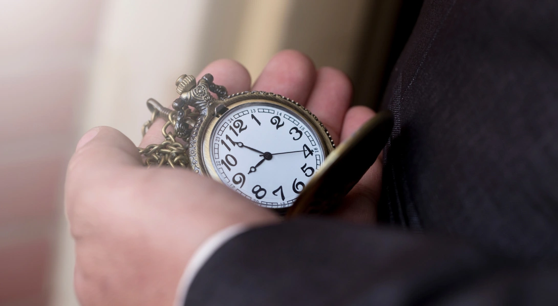 Man in formal suit holding pocket watch in gloved hand