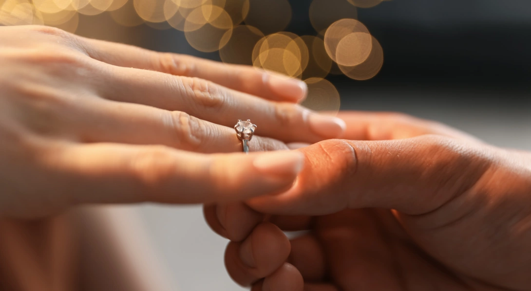 Man putting ring on woman’s finger