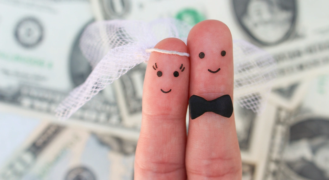 Bride and groom figures drawn on fingers with money background